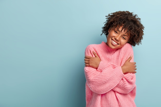 Photo gratuite concept d'amour, de soins et de tendresse. heureuse jeune femme aux boucles sombres, s'embrasse, touche les épaules et incline la tête