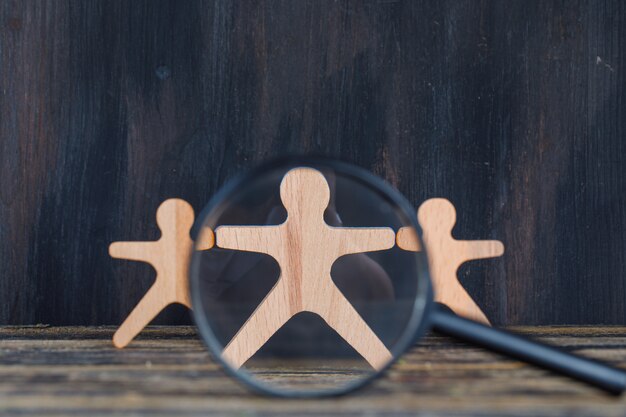Concept d'analyse marketing avec loupe sur une figure en bois sur close-up de fond en bois et grunge.