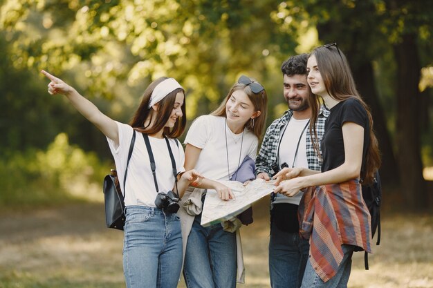 Concept d'aventure, de voyage, de tourisme, de randonnée et de personnes. Groupe d'amis souriants dans une forêt. Homme avec binocularus.