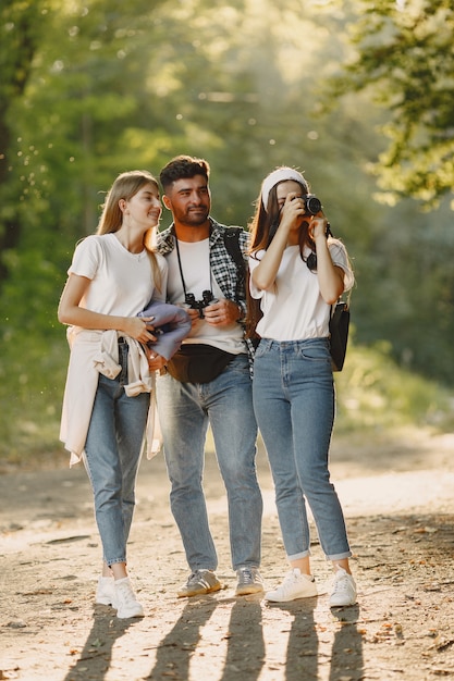 Concept d'aventure, de voyage, de tourisme, de randonnée et de personnes. Groupe d'amis souriants dans une forêt.