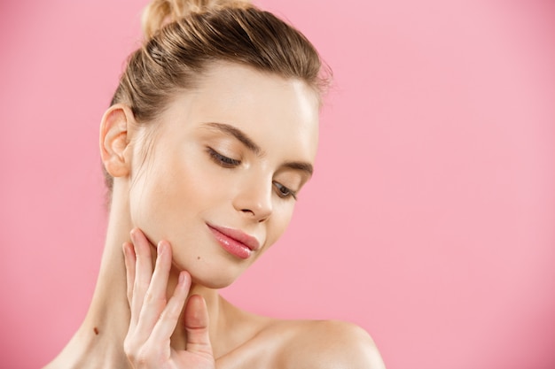 Concept de beauté - Close up Portrait d&#39;une fille caucasienne attrayante avec une peau naturelle de beauté isolée sur fond rose avec un espace de copie.