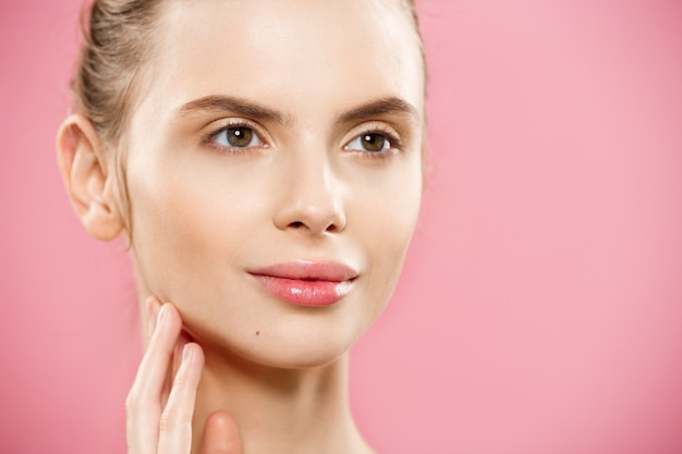 Concept de beauté - Close up Portrait d&#39;une fille caucasienne attrayante avec une peau naturelle de beauté isolée sur fond rose avec un espace de copie.