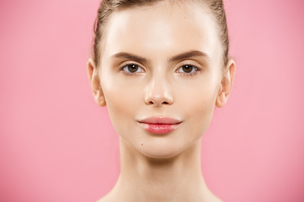 Concept de beauté - Close up Portrait d&#39;une fille caucasienne attrayante avec une peau naturelle de beauté isolée sur fond rose avec un espace de copie.