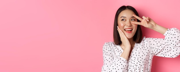 Photo gratuite concept de beauté et de style de vie gros plan d'une jolie femme asiatique montrant un signe de paix et touchant la joue smi