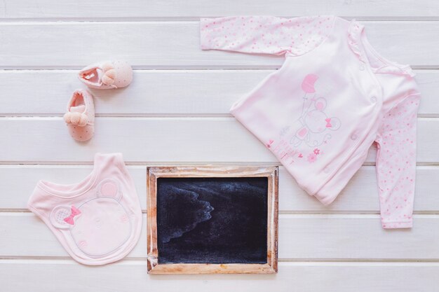 Concept bébé avec ardoise et vêtements pour bébés