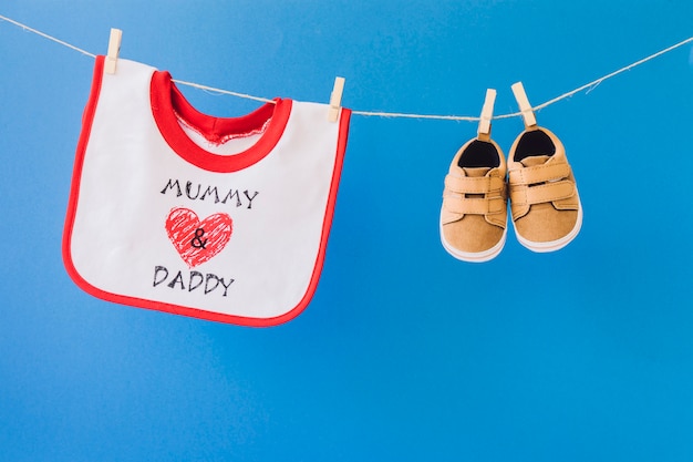 Concept bébé avec bavoir et chaussures suspendues à la corde à linge