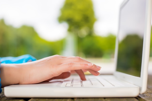 Concept de bureau en plein air, main féminine à l&#39;aide d&#39;un ordinateur portable