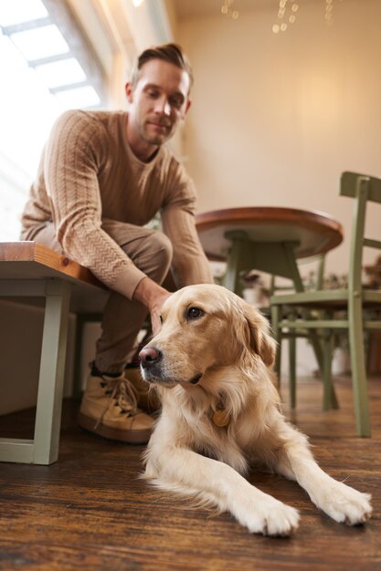 Un concept de café adapté aux chiens. Un bel homme, propriétaire d'un golden retriever, est assis dans un café avec ses boissons pour animaux de compagnie.