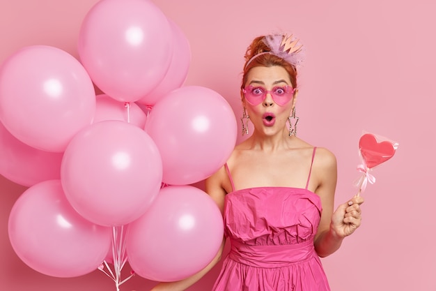 Concept de célébration. Une femme européenne rousse stupéfaite garde la bouche ouverte regarde les yeux écarquillés