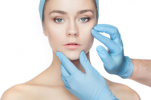Concept de chirurgie plastique mains de docteur dans des gants touchant le visage de femme