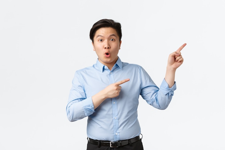 Photo gratuit concept commercial, financier et humain. un entrepreneur asiatique surpris et impressionné, un directeur de bureau en chemise bleue pointant vers le coin supérieur droit et l'air émerveillé, dites wow et regardez la caméra avec admiration