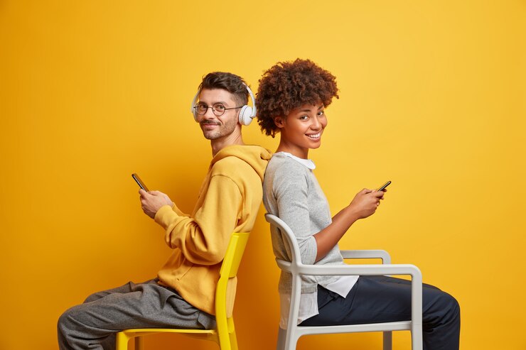 Photo gratuit concept de dépendance et de style de vie de gadget. couple interracial heureux détendu s'asseoir l'un à l'autre ignorer la communication en direct utiliser les téléphones mobiles modernes