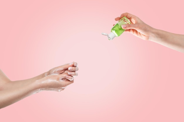 Concept de désinfection et de protection contre les bactéries et les virus. les mains des femmes sont lavées avec du savon en bas et les mains des femmes avec du gel antibactérien en haut. gros plan des mains. fond rose.