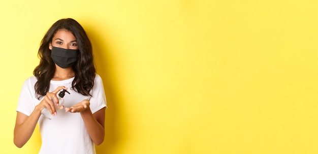 Photo gratuite le concept de distanciation sociale covid et l'image de style de vie d'une fille afro-américaine portant un masque facial en utilisant des ha