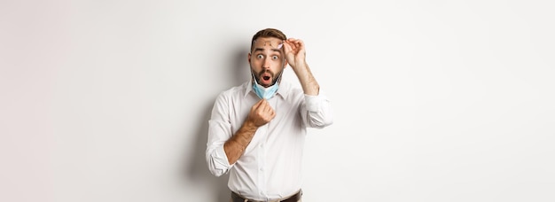 Le concept de distanciation sociale et de quarantaine de Covid a surpris l'homme au décollage masque facial et lunettes à la recherche d'un