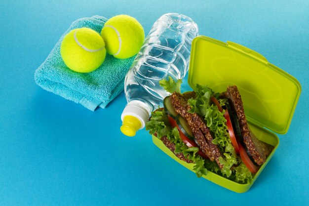 Concept du sport vie saine. Baskets avec balles de tennis, serviettes et bouteille d&#39;eau sur fond jaune clair. Espace de copie.