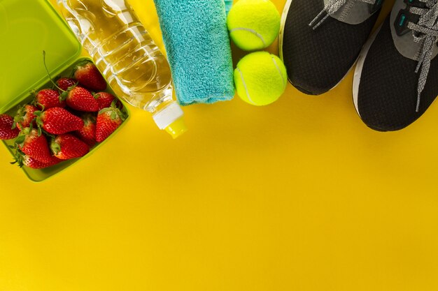 Concept du sport vie saine. Sneakers avec des fruits, des serviettes et une bouteille d&#39;eau sur fond en bois. Espace de copie.