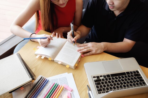 Concept d&#39;éducation. Étudiant étudiant et faisant un remue-méninges sur le concept du campus. Gros plan des étudiants qui discutent de leur sujet sur des livres ou des manuels scolaires. Mise au point sélective.