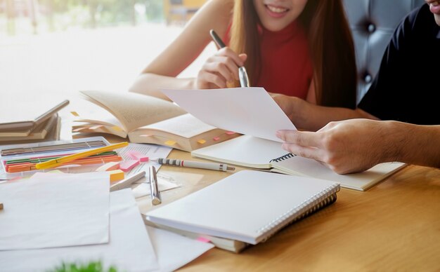 Concept d&#39;éducation. Étudiant étudiant et faisant un remue-méninges sur le concept du campus. Gros plan des étudiants qui discutent de leur sujet sur des livres ou des manuels scolaires. Mise au point sélective.