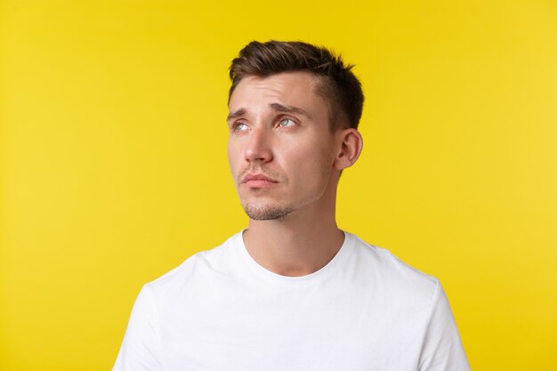 Concept d'émotions de mode de vie, d'été et de personnes. Portrait d'un jeune homme fatigué et en détresse, regardant dans le coin supérieur gauche avec une expression épuisée, se sentant déprimé ou solitaire.