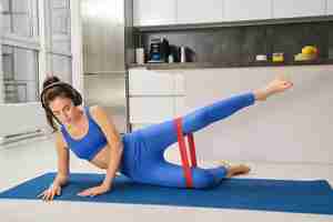 Photo gratuite concept d'entraînement et de remise en forme femme avec des écouteurs fait des exercices à la maison étirement résistance au caoutchouc