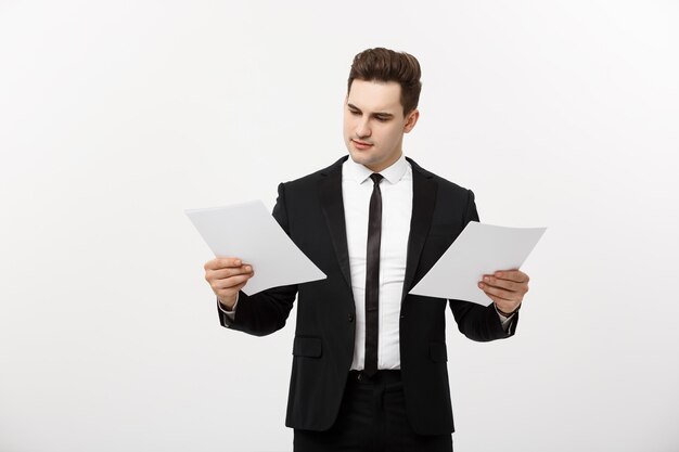 Concept d'entreprise : bel homme d'affaires attentif travaillant en comparant le rapport papier. Isolé sur fond gris blanc.