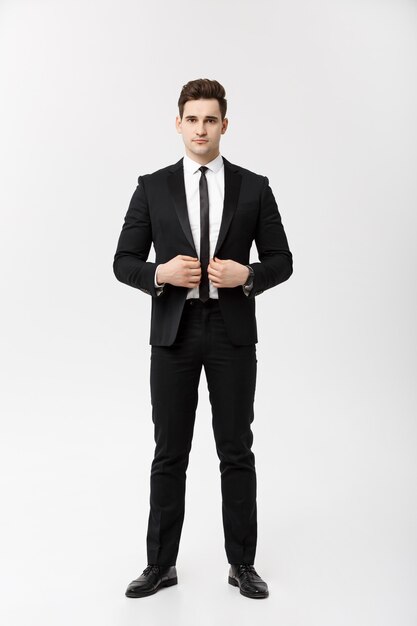 Concept d'entreprise : bel homme sourire heureux jeune beau mec en costume intelligent posant sur fond gris isolé.