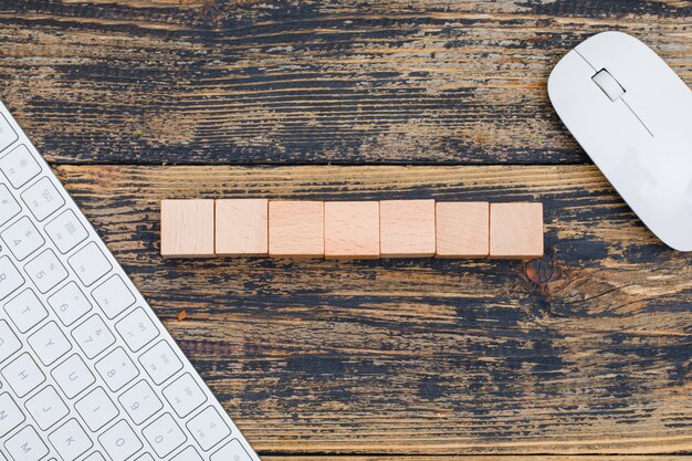 Concept d'entreprise avec des cubes en bois, souris d'ordinateur et clavier sur fond plat en bois.