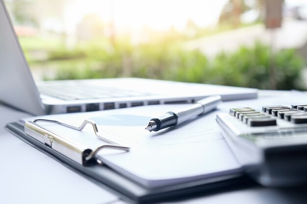 Concept d&#39;entreprise avec espace de copie. Table de bureau avec stylo et tableau d&#39;analyse, ordinateur, ordinateur portable, tasse de café sur le bureau. Tonalité de rétro Filtre rétro, mise au point sélective.