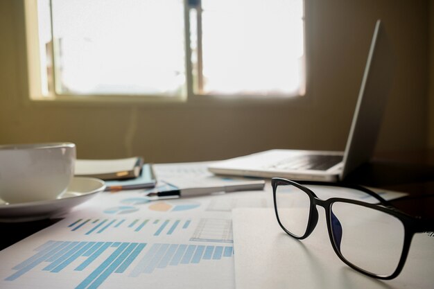 Concept d&#39;entreprise avec espace de copie. Table de bureau avec stylo et tableau d&#39;analyse, ordinateur, ordinateur portable, tasse de café sur le bureau. Tonalité de rétro Filtre rétro, mise au point sélective.