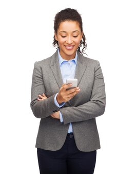 Concept d'entreprise, d'internet et de technologie - femme afro-américaine souriante regardant un smartphone