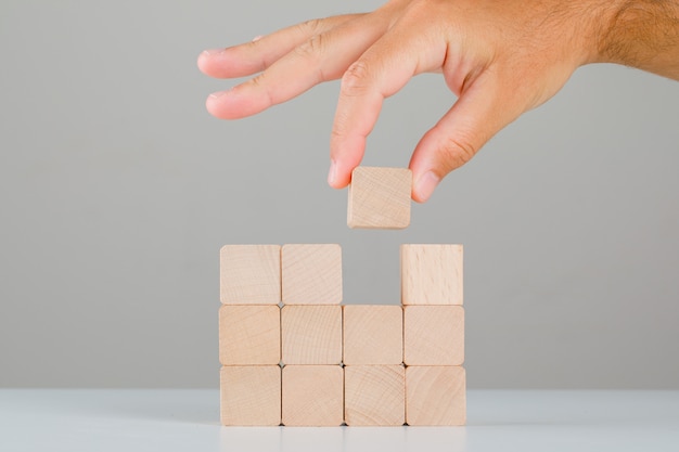 Concept d'entreprise sur la vue de côté de table blanche et grise. main tirant ou plaçant un cube en bois.