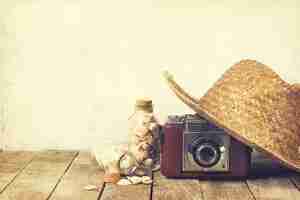 Photo gratuite concept d'été ou de vacances. chapeau de paille avec vieille caméra vintage et coquilles sur fond en bois.