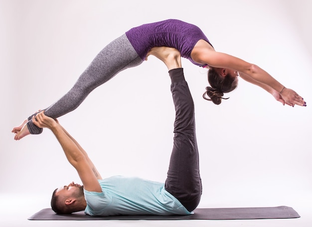 Photo gratuite concept d'exercices de yoga. jeune couple en bonne santé en position d'yoga sur fond blanc