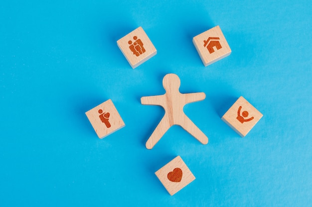 Concept de famille avec des icônes sur des cubes en bois, figure humaine sur table bleue à plat.