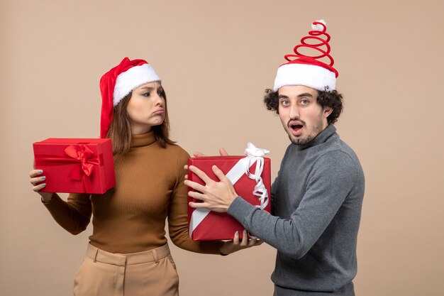 Concept festif de nouvel an humeur avec drôle cool couple charmant portant des chapeaux de père Noël rouge sur fond gris