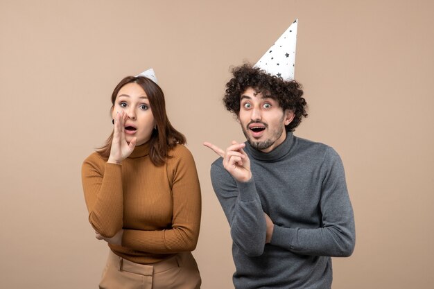 Concept de fête et de fête de vacances - heureux émotionnel excité surpris charmant jeune couple parlant de quelque chose sur gris