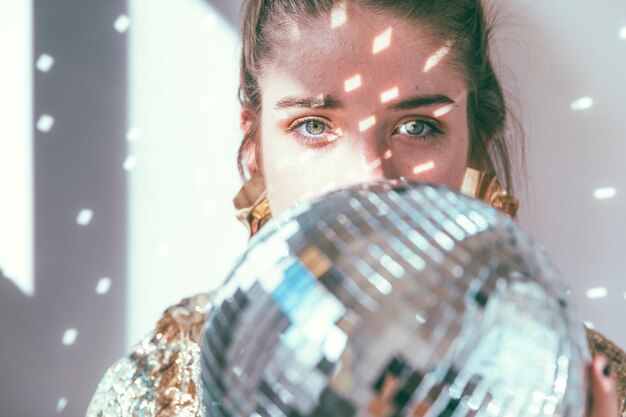 Concept de fête de nouvel an avec une fille derrière une boule disco