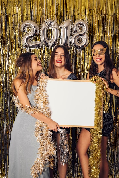 Concept de fête de nouvel an avec des filles montrant le tableau blanc