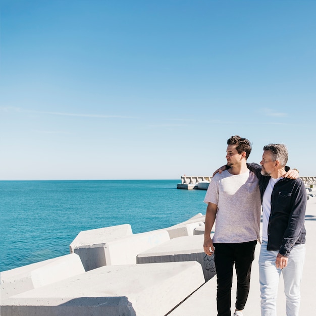 Concept De Fête Des Pères Avec Père Et Fils Marchant à Côté De La Mer