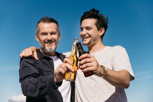 Concept de fête des pères avec souriant père et fils grillage avec de la bière