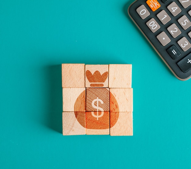 Concept financier avec icône sur cubes en bois, calculatrice sur table turquoise télévision lay.