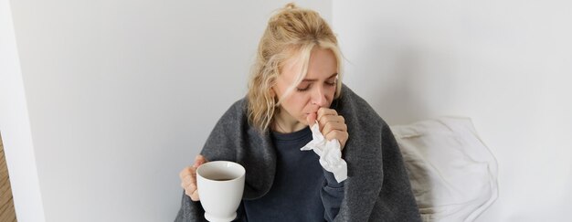 Photo gratuite concept de grippe et de quarantaine portrait en gros plan d'une jeune femme qui se sent malade, qui attrape un rhume et qui éternue