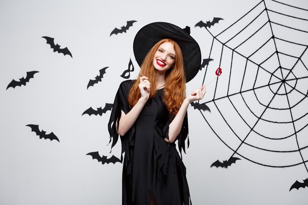 Concept d'Halloween - Belles filles en robes de sorcière noires tenant des accessoires de fête.