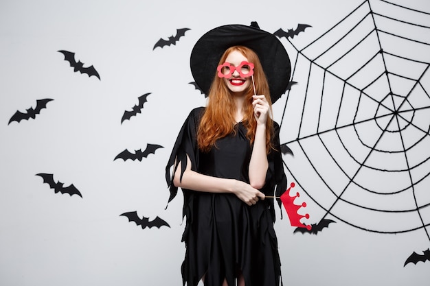 Concept d'Halloween - Belles filles en robes de sorcière noires tenant des accessoires de fête.
