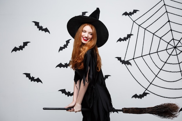 Concept d'Halloween, une sorcière élégante et heureuse aime jouer avec un manche à balai