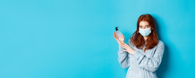 Photo gratuite concept d'hiver covid et de distanciation sociale jeune fille rousse en masque facial montrant un désinfectant pour les mains de