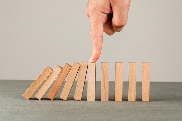 Concept d'idée d'entreprise sur la vue latérale du mur gris et blanc. main arrêtant l'effet domino.