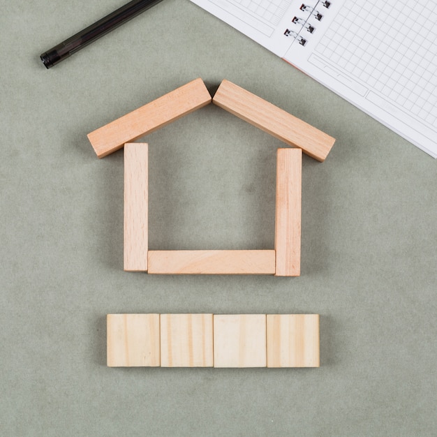 Concept immobilier avec des blocs de bois, carnet, stylo sur gros plan fond gris.