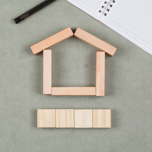 Concept immobilier avec des blocs de bois, carnet, stylo sur gros plan fond gris.